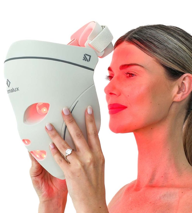 Woman holding the Dermalux LED Face Mask to her face at home